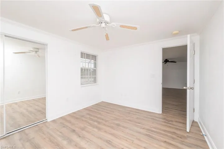 Unfurnished bedroom featuring ceiling fan, a closet, light wood-type flooring, and ornamental molding
