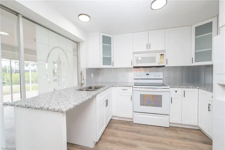 Kitchen with white cabinets, white appliances, sink, and tasteful backsplash