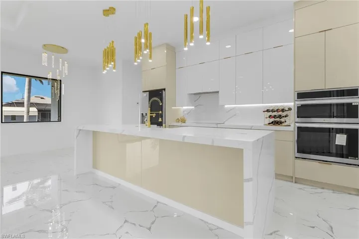 Kitchen featuring light marble finish floors, modern cabinets, hanging light fixtures, and stainless steel appliances