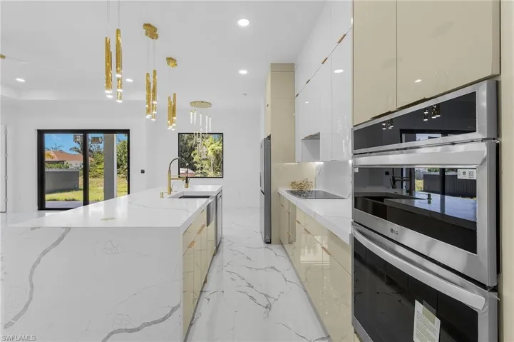Kitchen with modern cabinets, stainless steel appliances, light marble finish flooring, recessed lighting, and light stone counters