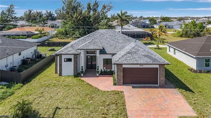 View of front of house with a residential view, a garage, decorative driveway, roof with shingles, and stucco siding