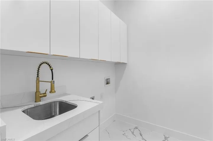 Laundry area featuring cabinet space, marble finish flooring, hookup for a washing machine, and hookup for an electric dryer