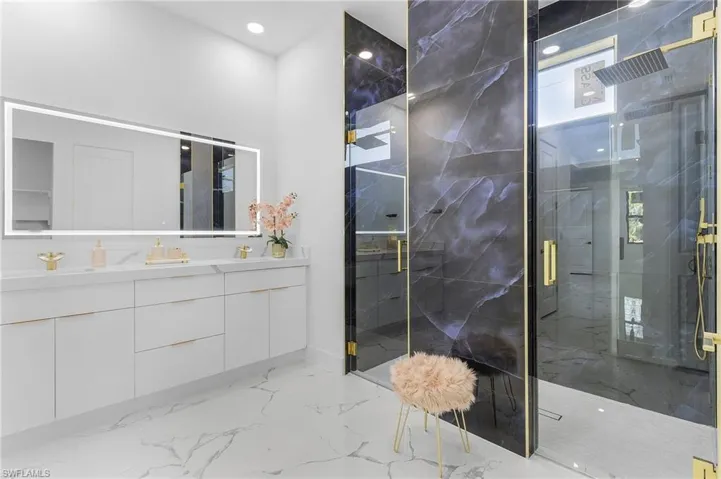 Bathroom with a marble finish shower, vanity, marble tiled floors, and recessed lighting