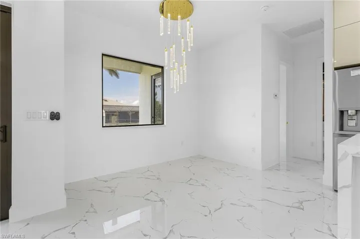 Unfurnished dining area featuring a chandelier and light marble finish flooring