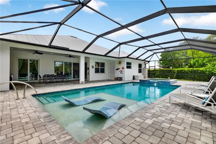 Custom pool with sun shelf, pool loungers, integrated spa, large screened enclosure and door into 3rd full bathroom