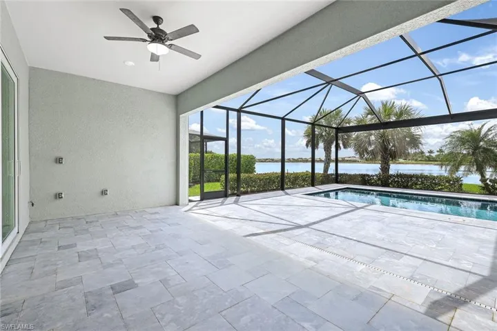 View of swimming pool featuring glass enclosure, a water view, a patio area, and ceiling fan
