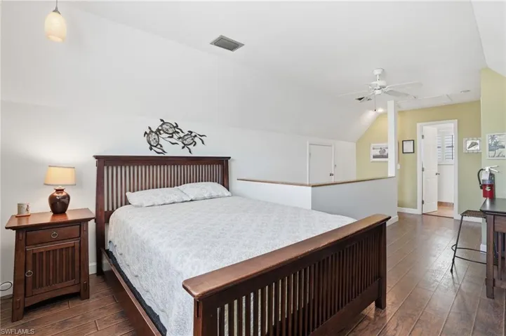 Bedroom featuring dark wood-style flooring, vaulted ceiling, and ceiling fan