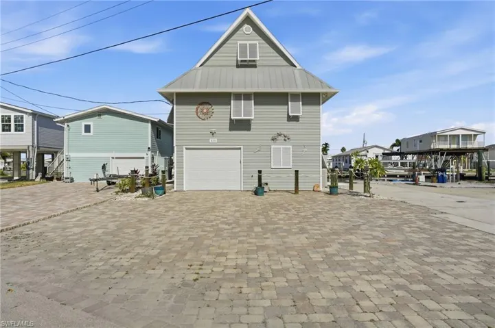 Back of property with a garage, driveway, a metal roof, and a residential view