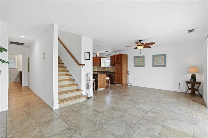 Unfurnished living room with stairs and a ceiling fan