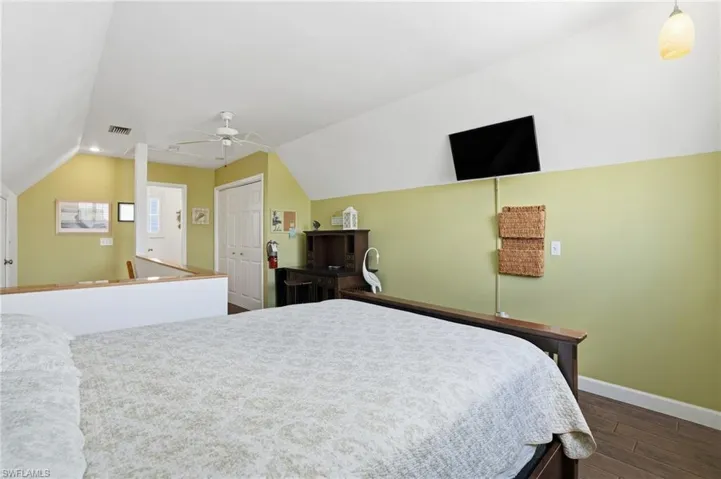 Bedroom with dark wood-style floors, a ceiling fan, a closet, and vaulted ceiling