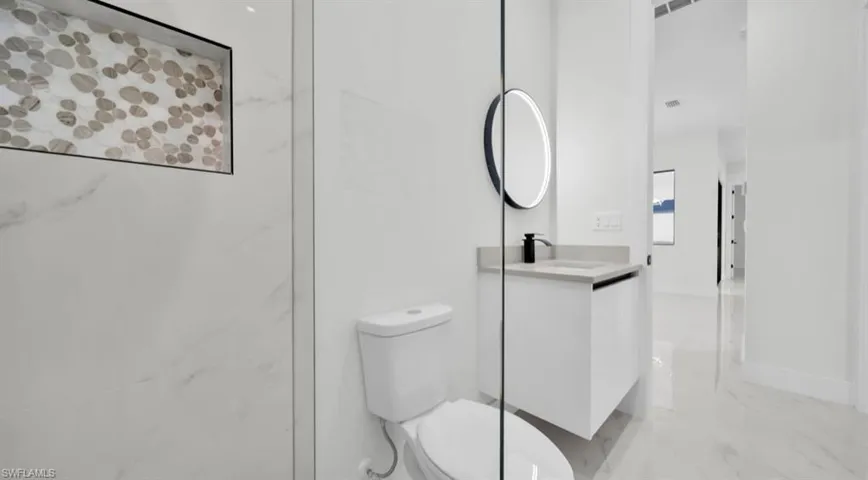 Full bath with light marble finish floors and vanity