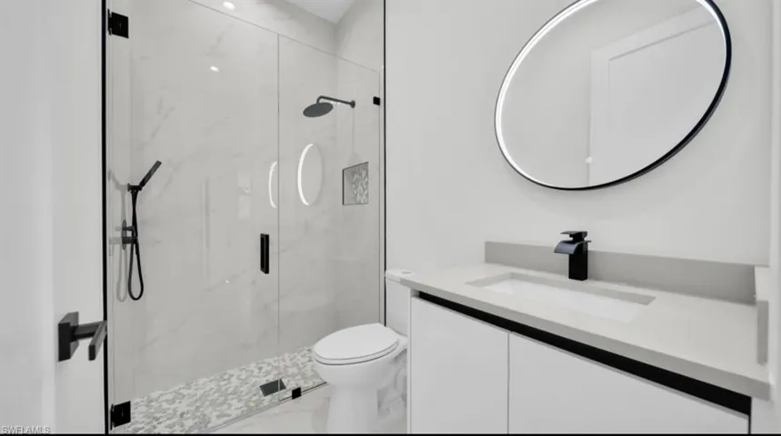 Bathroom with vanity, a marble finish shower, and marble look tile flooring