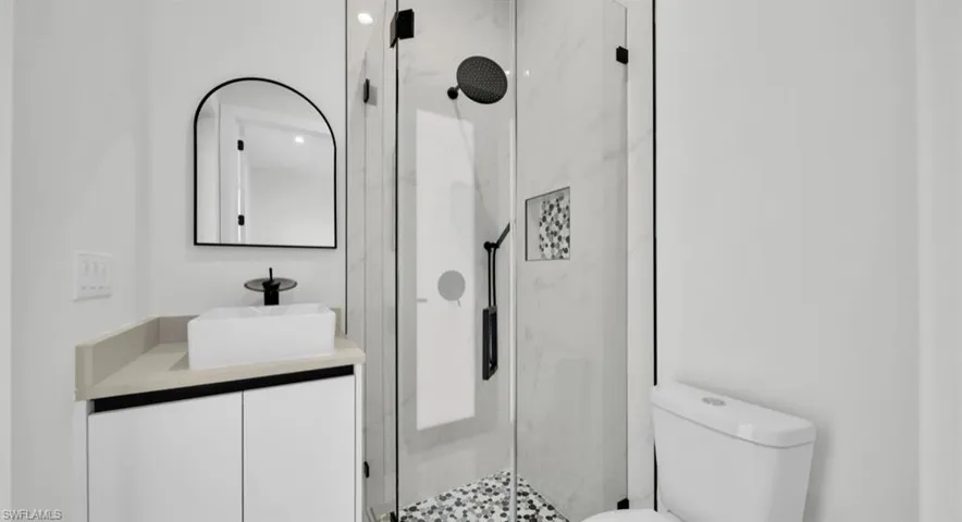 Bathroom with vanity and a marble finish shower