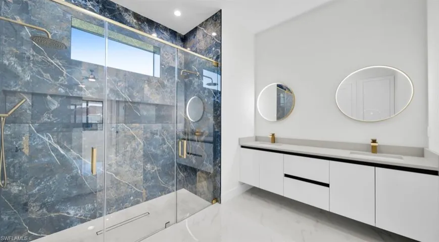 Bathroom with light marble finish floors, double vanity, a marble finish shower, and recessed lighting