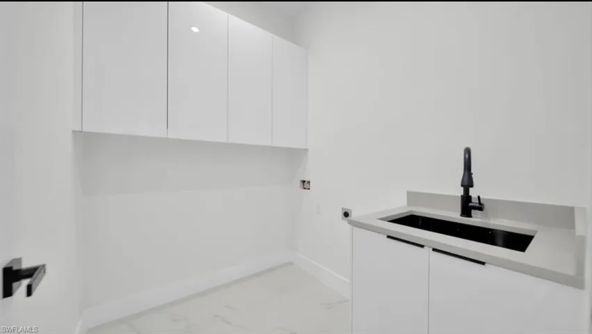 Laundry room featuring light marble finish flooring, cabinet space, and washer hookup
