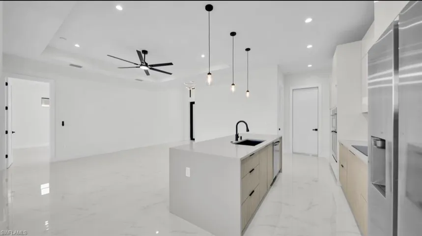 Kitchen with recessed lighting, stainless steel appliances, modern cabinets, pendant lighting, and light stone countertops