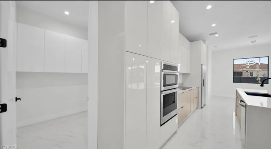 Kitchen featuring modern cabinets, light marble finish floors, white cabinetry, and recessed lighting