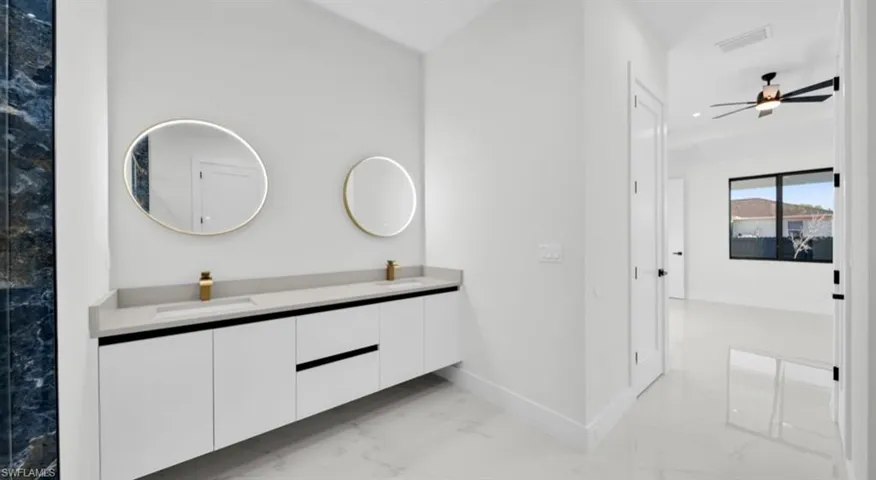Bathroom featuring light marble finish floors, double vanity, a ceiling fan, and recessed lighting
