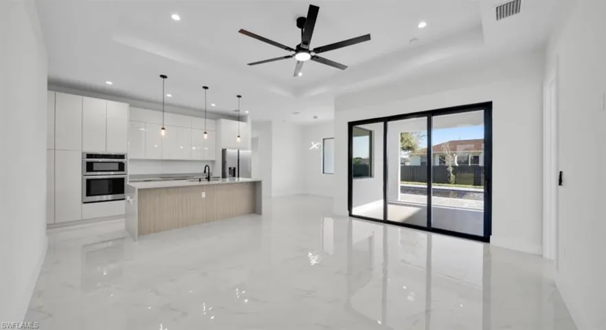 Kitchen featuring modern cabinets, white cabinetry, a tray ceiling, and recessed lighting