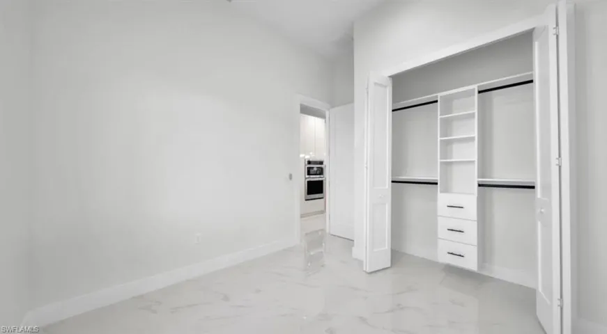 Unfurnished bedroom with a closet and light marble finish flooring