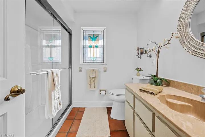 Bathroom with vanity, toilet, an enclosed shower, and tile patterned flooring