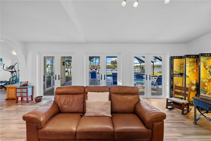 Living room with vaulted ceiling, light wood-type flooring, and french doors