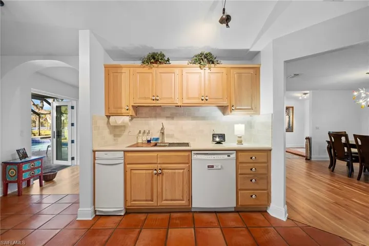 Kitchen with tasteful backsplash, light brown cabinetry, dishwasher, and sink