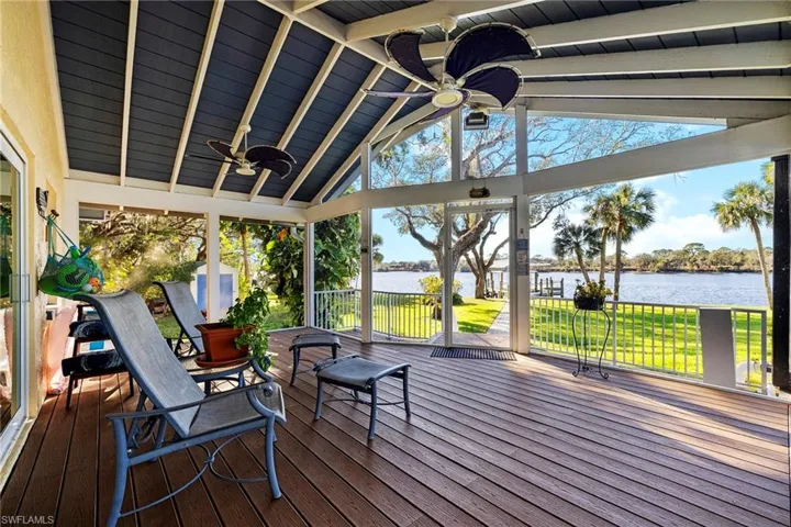 Deck with a water view, ceiling fan, and a lawn