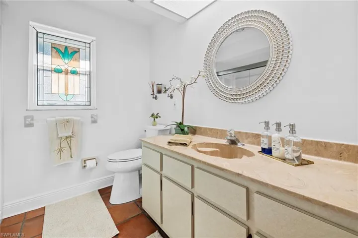 Bathroom featuring vanity, toilet, a skylight, and tile patterned flooring