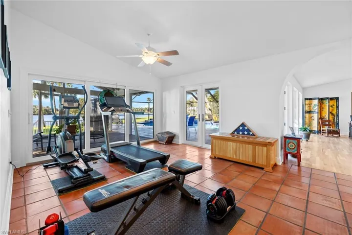 Workout area featuring lofted ceiling, tile patterned flooring, french doors, and ceiling fan