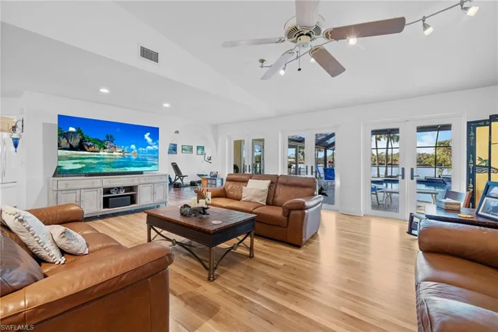 Living room with french doors, ceiling fan, lofted ceiling, and light wood-type flooring