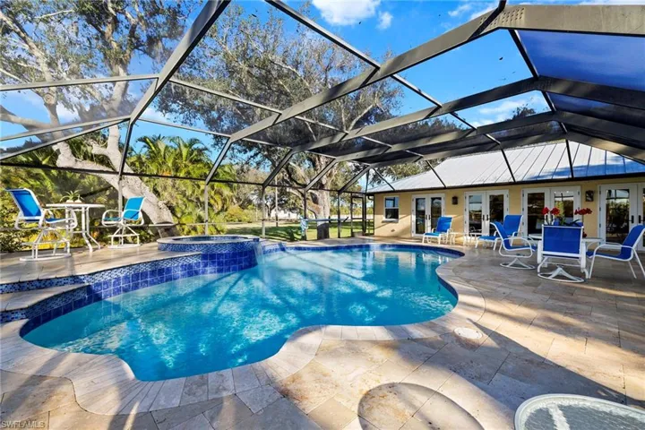 View of pool with an in ground hot tub, a patio, glass enclosure, and french doors