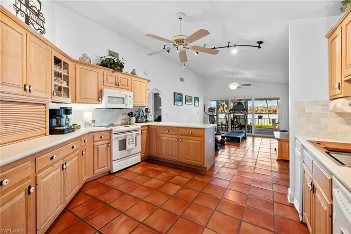Kitchen featuring white appliances, kitchen peninsula, decorative backsplash, and light brown cabinets