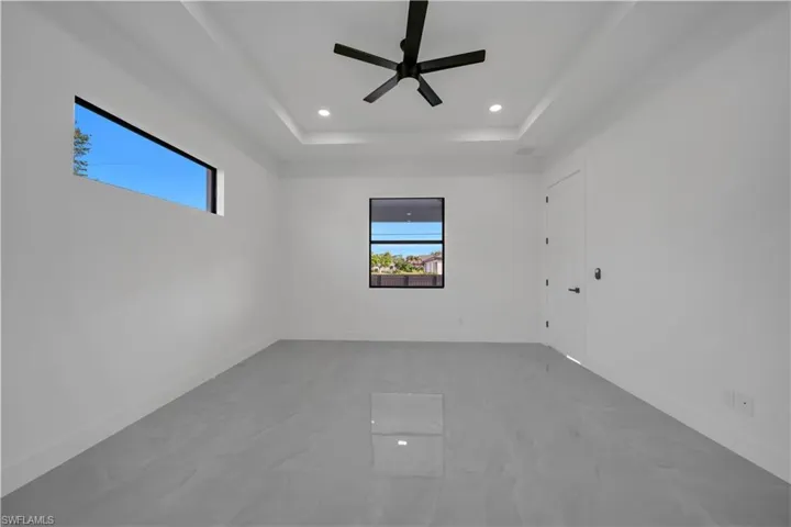 Spare room with plenty of natural light, a raised ceiling, recessed lighting, ceiling fan, and baseboards