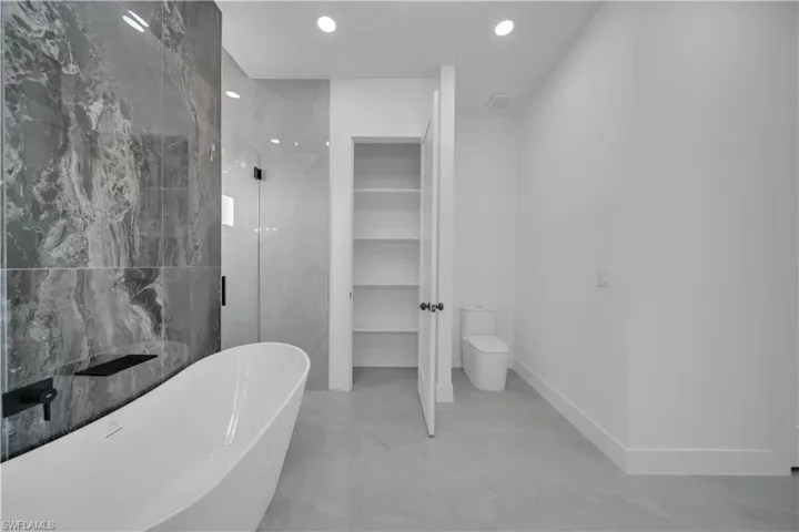 Full bath featuring a freestanding tub, a shower stall, toilet, and recessed lighting