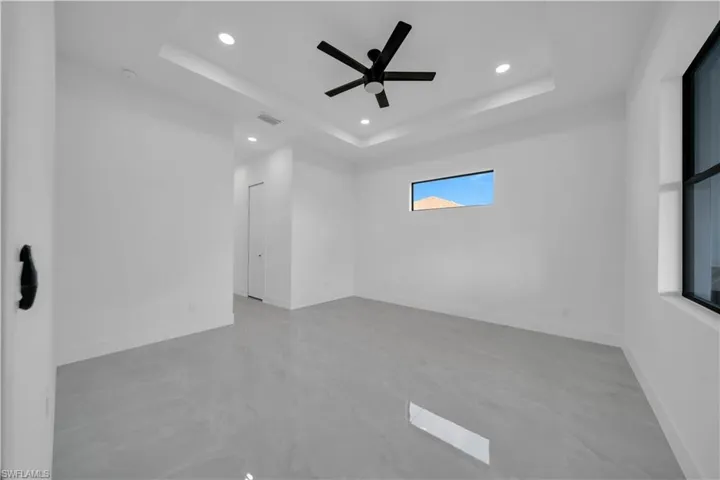 Unfurnished room featuring recessed lighting, a raised ceiling, a ceiling fan, concrete flooring, and baseboards