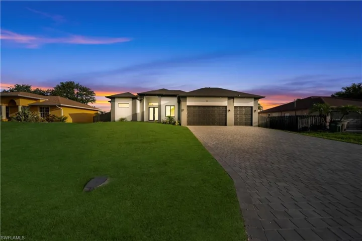 View of front of house featuring decorative driveway, a garage, and stucco siding