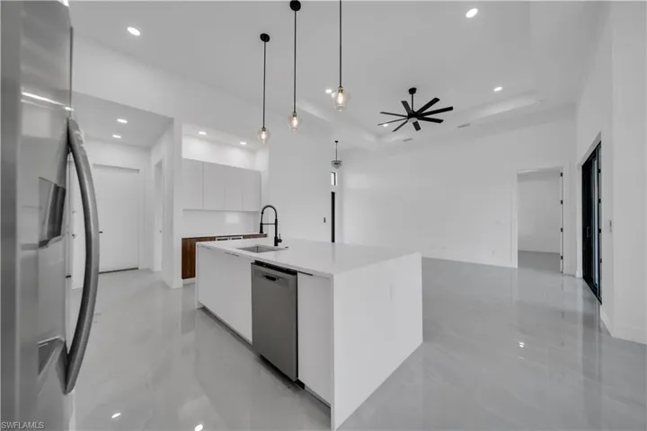 Kitchen with modern cabinets, appliances with stainless steel finishes, a sink, recessed lighting, and a raised ceiling