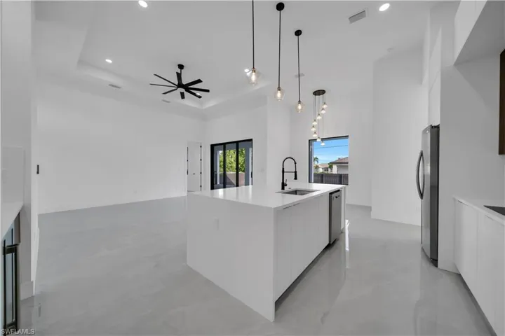 Kitchen with modern cabinets, a sink, freestanding refrigerator, white cabinets, and recessed lighting