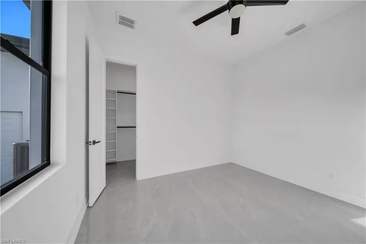 Unfurnished bedroom with a walk in closet, a ceiling fan, baseboards, and a closet