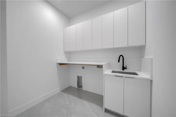 Laundry area featuring electric dryer hookup, cabinet space, and baseboards