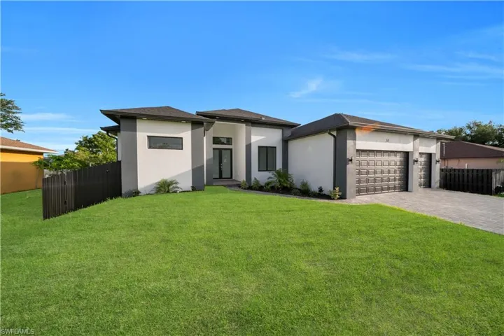 Prairie-style house featuring an attached garage, stucco siding, and decorative driveway
