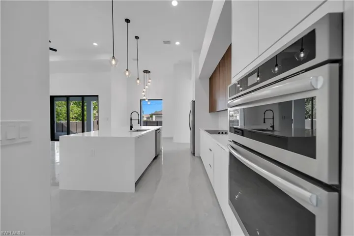 Kitchen featuring modern cabinets, appliances with stainless steel finishes, a sink, white cabinetry, and light countertops