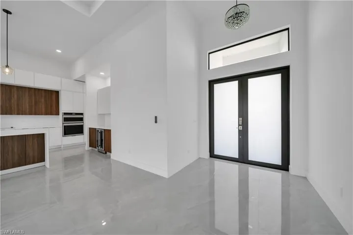Foyer featuring light marble finish floors, a towering ceiling, baseboards, french doors, and recessed lighting