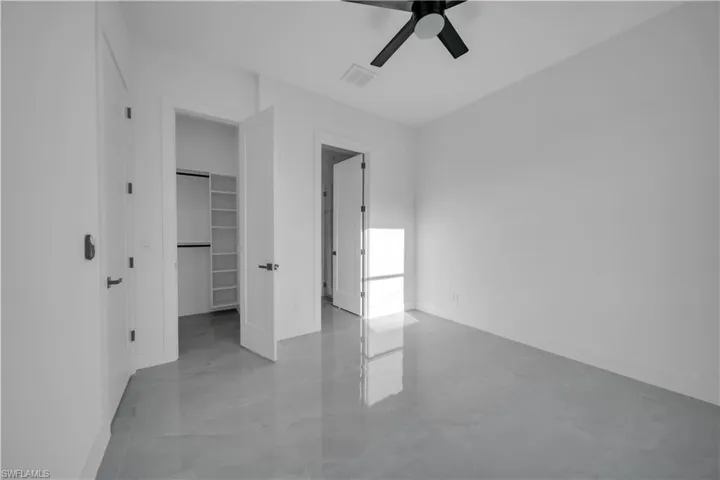 Unfurnished bedroom with baseboards, a spacious closet, a ceiling fan, and a closet