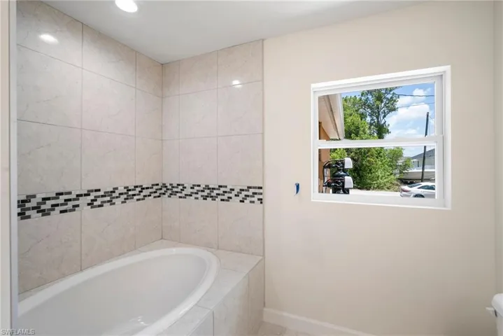 Bathroom featuring a relaxing tiled bath and toilet