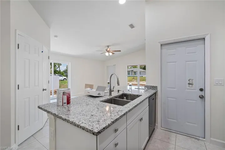 Kitchen with light tile flooring, kitchen peninsula, ceiling fan, sink, and lofted ceiling