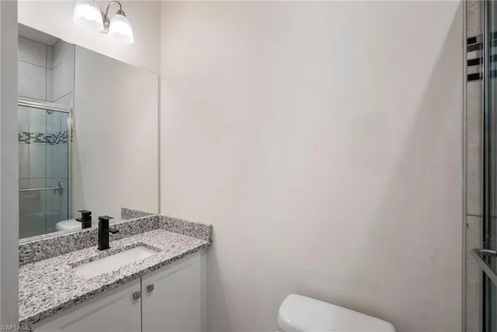 Bathroom with an enclosed shower, vanity, and toilet