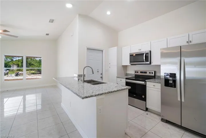 Kitchen featuring a center island with sink, appliances with stainless steel finishes, white cabinets, sink, and ceiling fan
