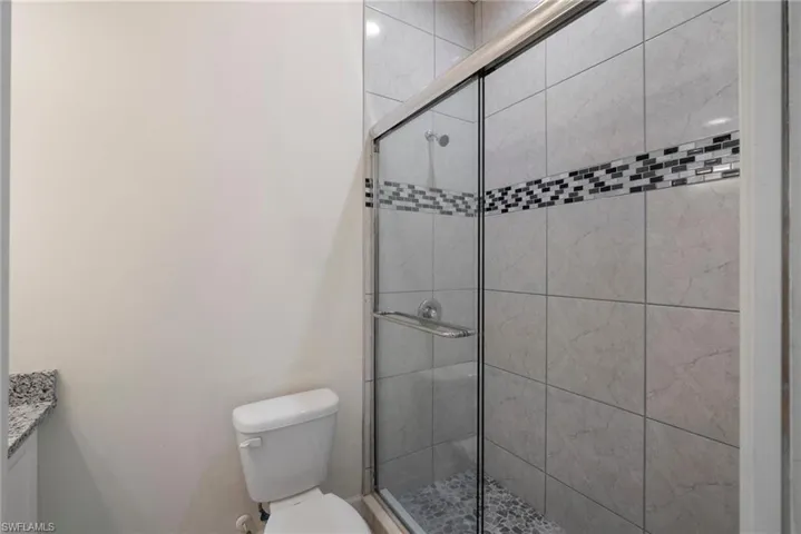 Bathroom featuring an enclosed shower, vanity, and toilet